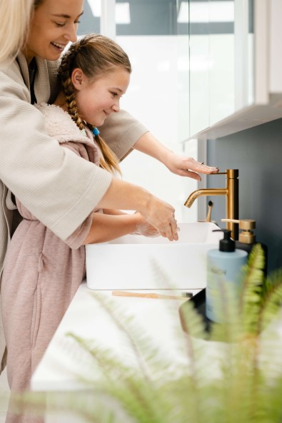 Woman and child using Clearlite tap in a bathroom